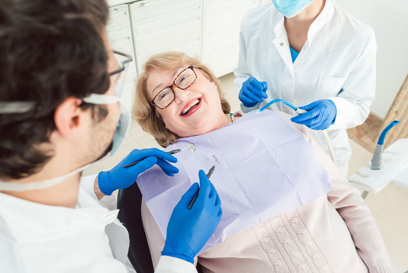 patient looking happy while dental staff members assist in dental treatment