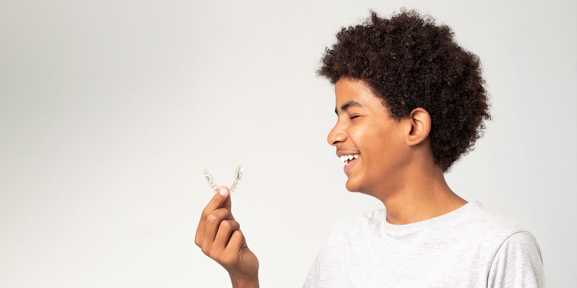 teenager smiling brightly with dental aligners
